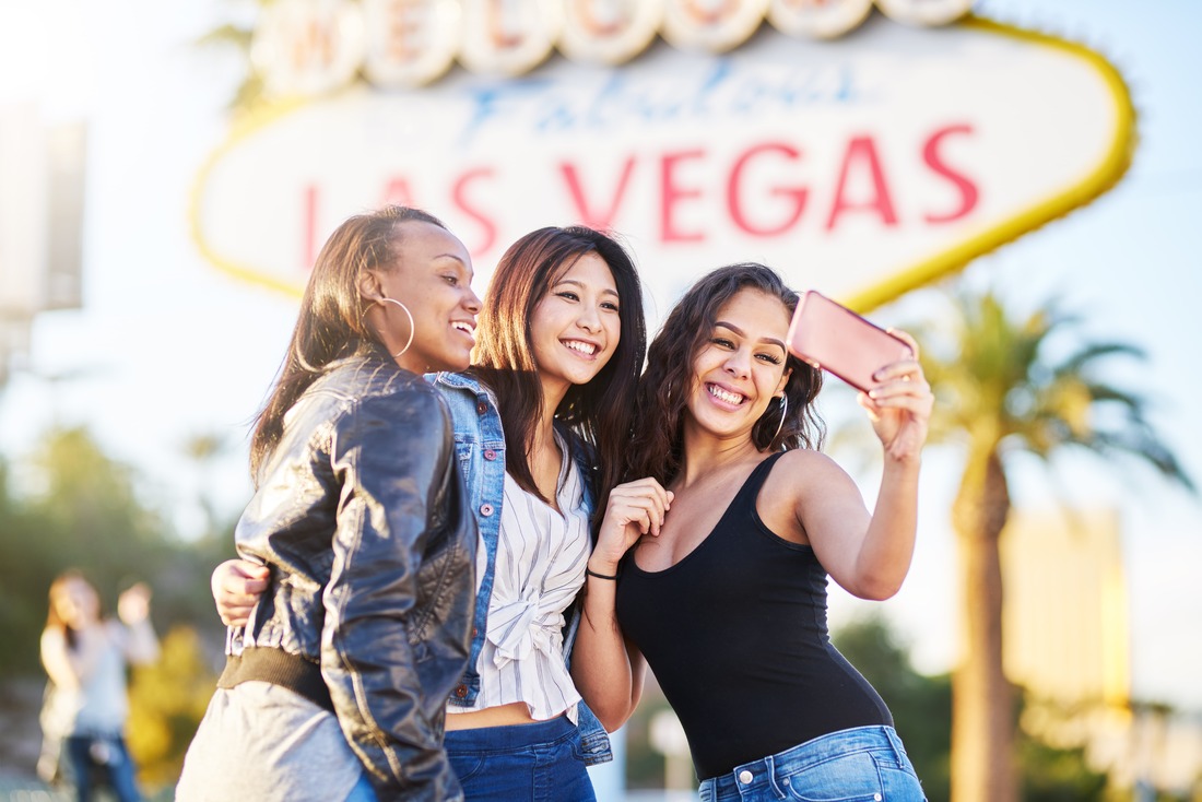girls posing for selfie in front of las vegas sign